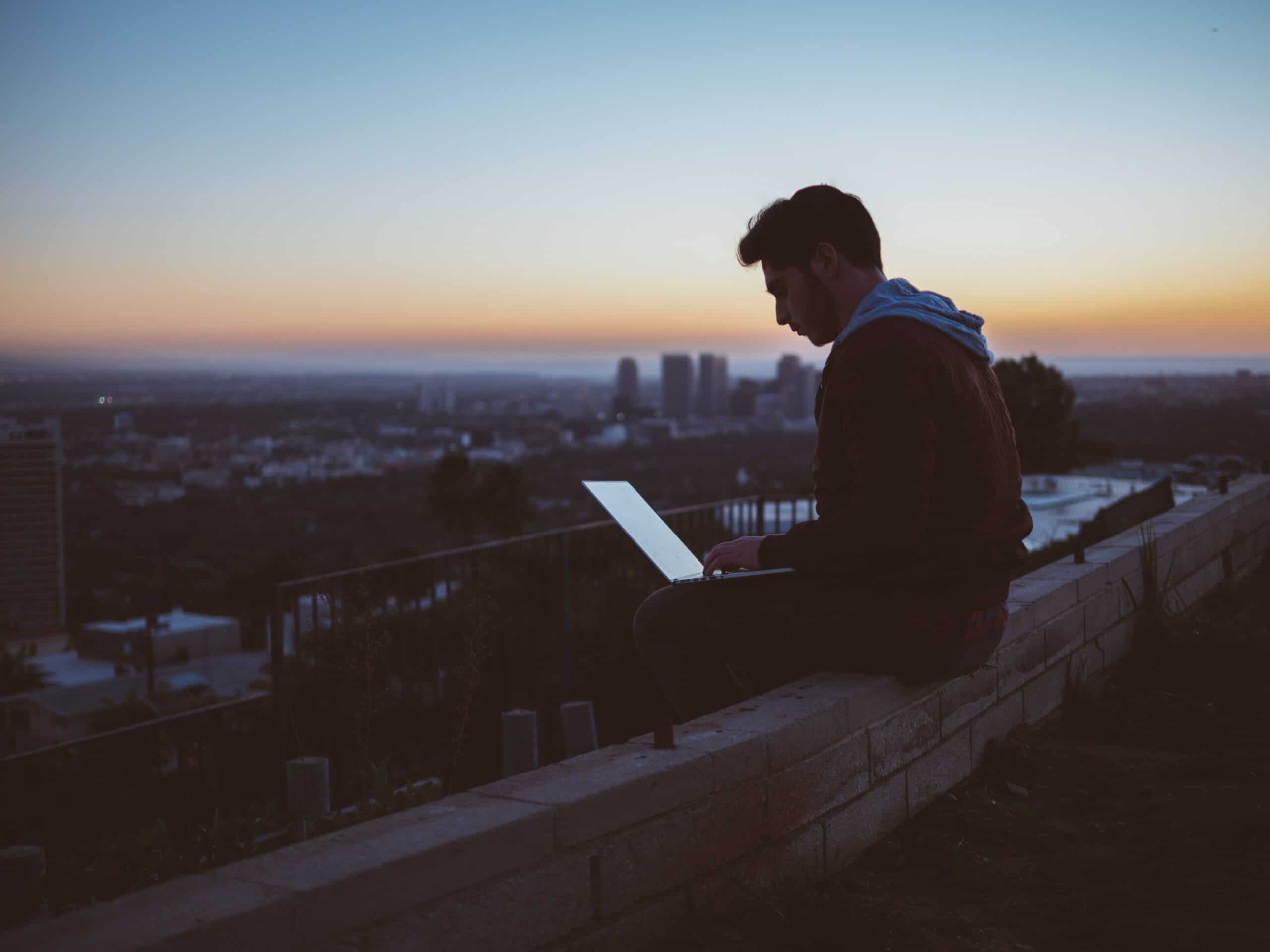 man working on his laptop at dusk sunset