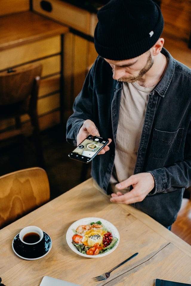 man taking picture of food with phone