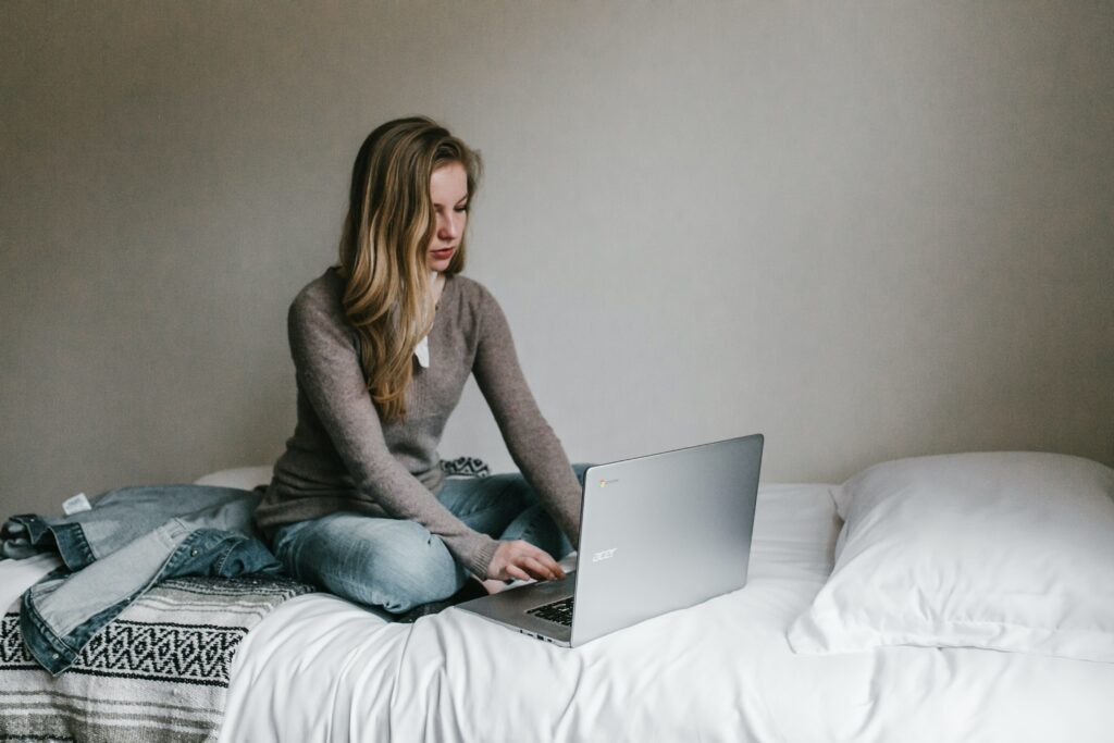 working remotely blonde female on bed